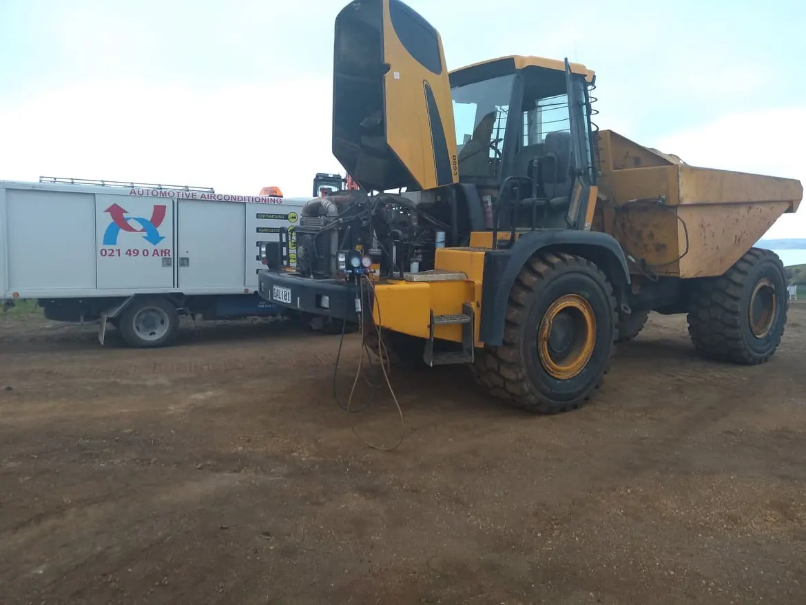 Articulated dump truck with its cab raised for on-site air conditioning repair